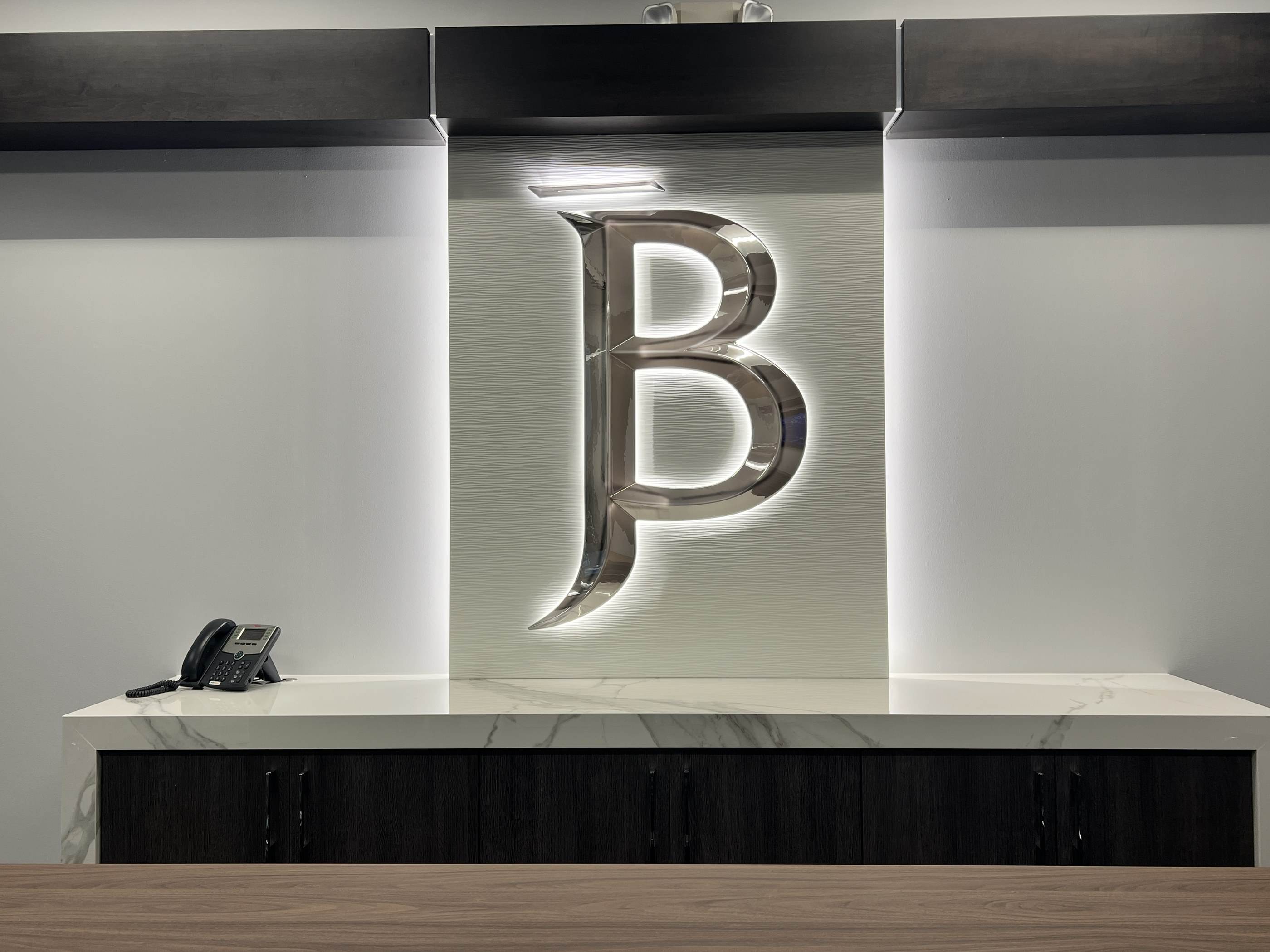 The backlit JB monogram above the conference credenza